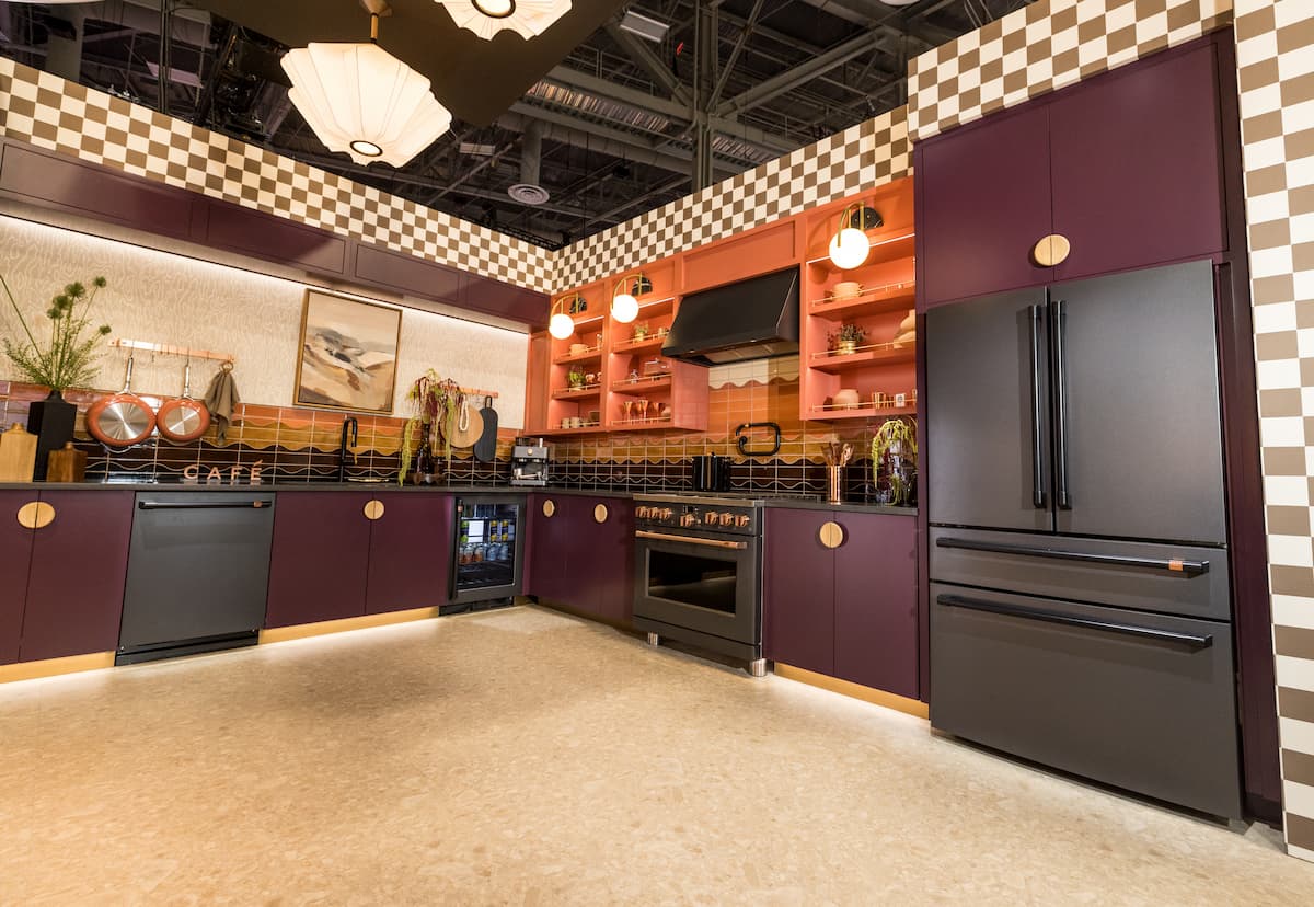 Kitchen vignette with black fridge, range, dishwasher and textured tile, checkered wallpaper