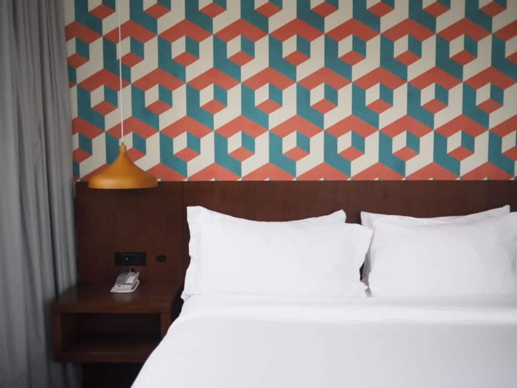 Patterned wallpaper over bright white bedding.