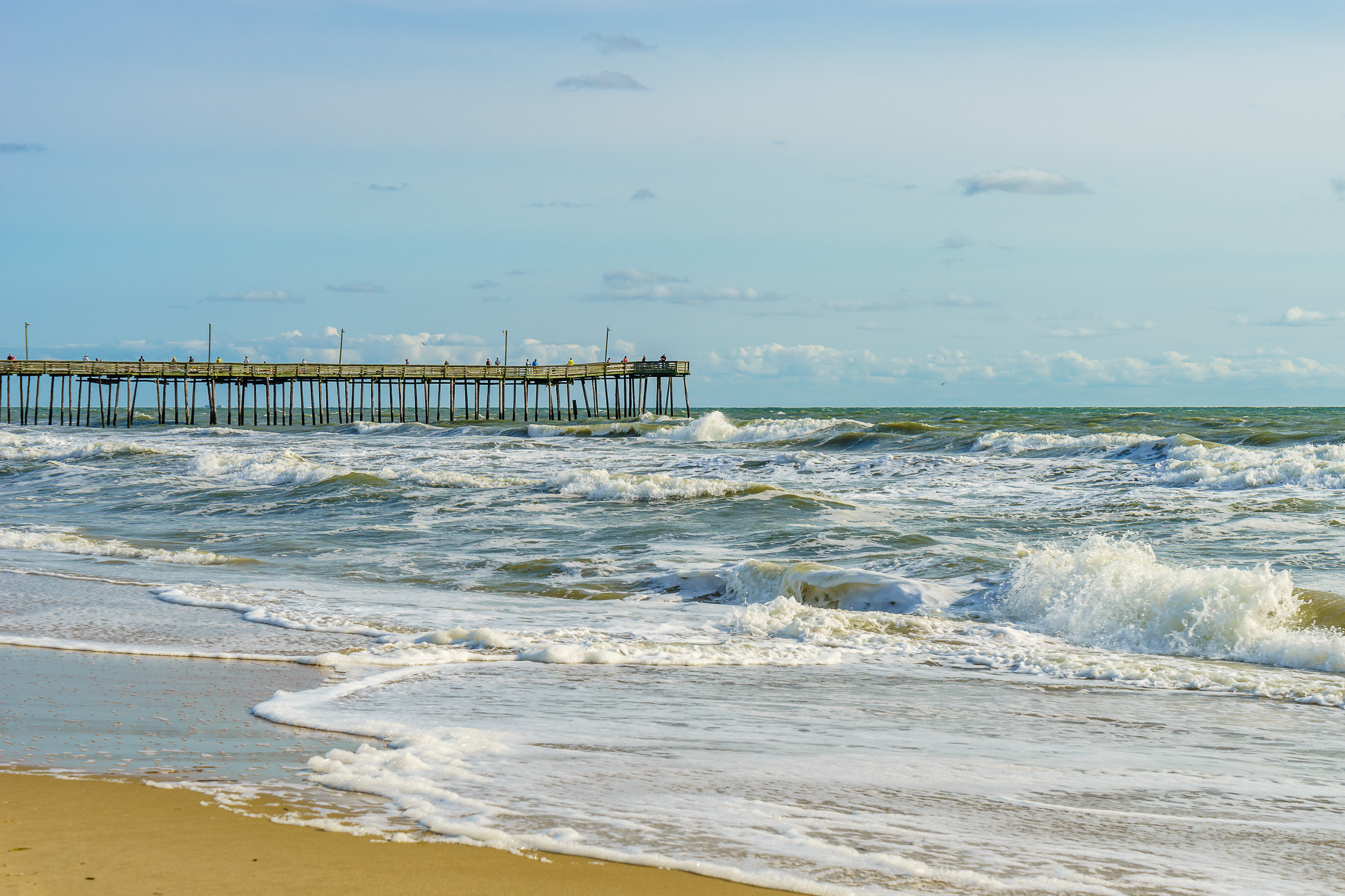 wooden pier jutting out into the frothy waves