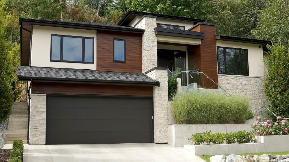 Modern home with dark wood and limestone siding and black accents.