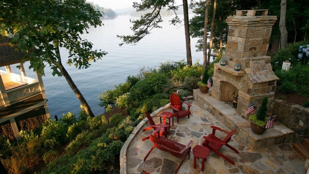 outdoor stone fireplace on a lake shoreline, with a seating area in a circle in front