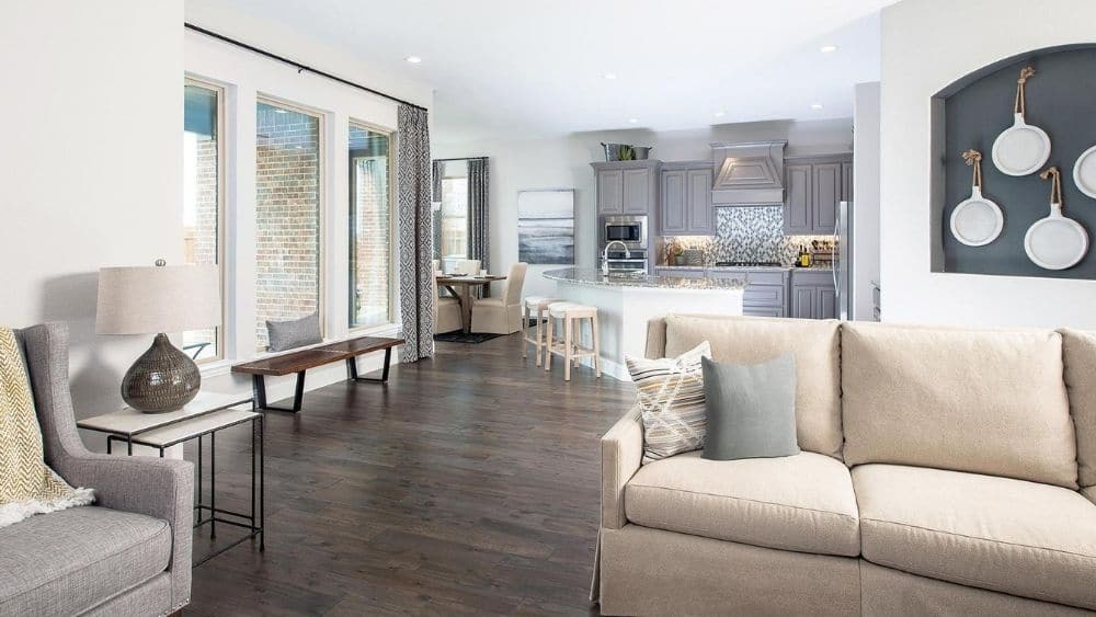 Furnished living room with high windows and an open layout that leads into a kitchen.