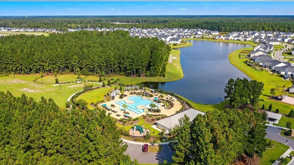Aerial view of a community with a pool, lots of greenspace, and a natural waterway.