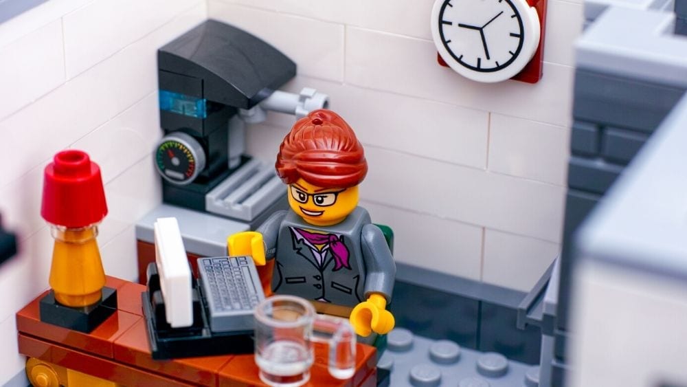 Lego figure sitting at a desk in a lego office