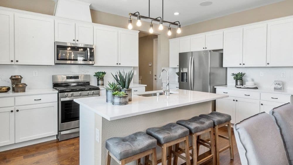 A modern kitchen with white countertops and cabinets and hardwood floors.