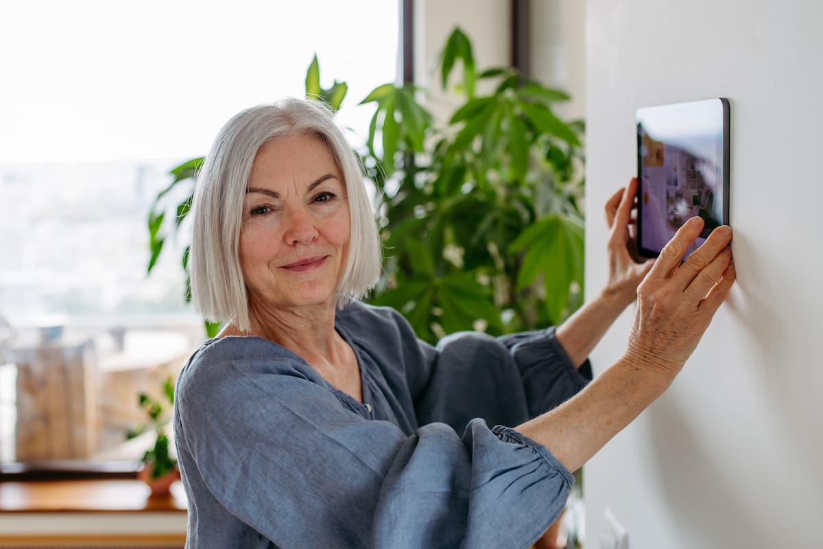 Mature woman adjusting a tablet for smart home technology controls