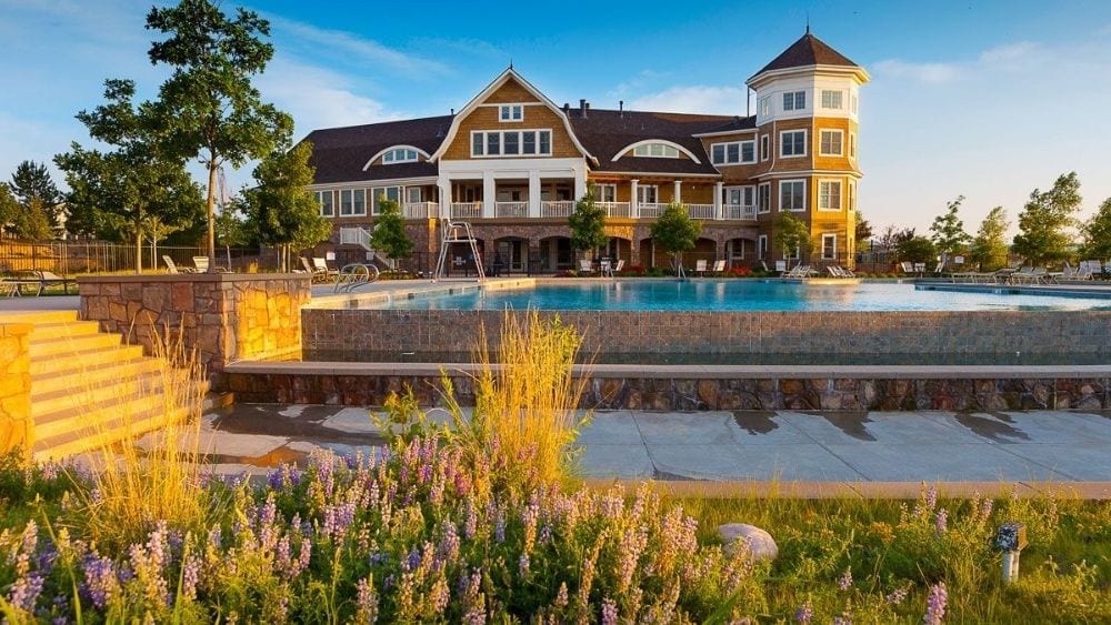 A community pool with a stately community center behind it.