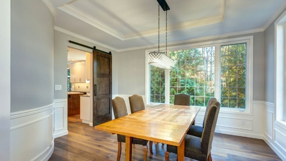 A dining room with a tray ceiling and large window.