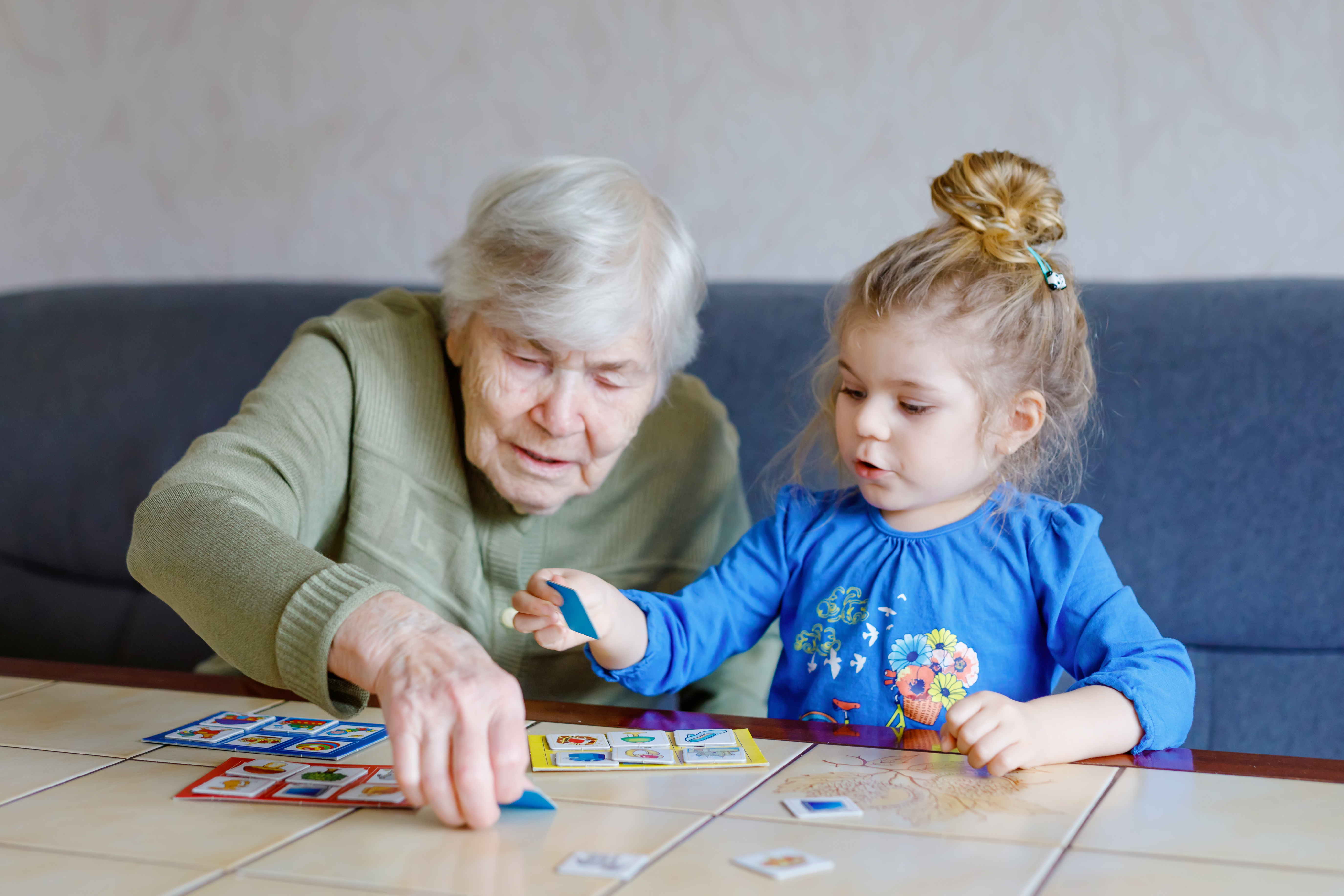 A grandmother and granddaughter playing a card game together on a table