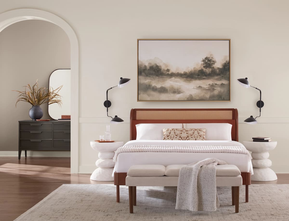 Bedroom painted in quiet luxury paint colors, with bed, landscape print and wall sconces