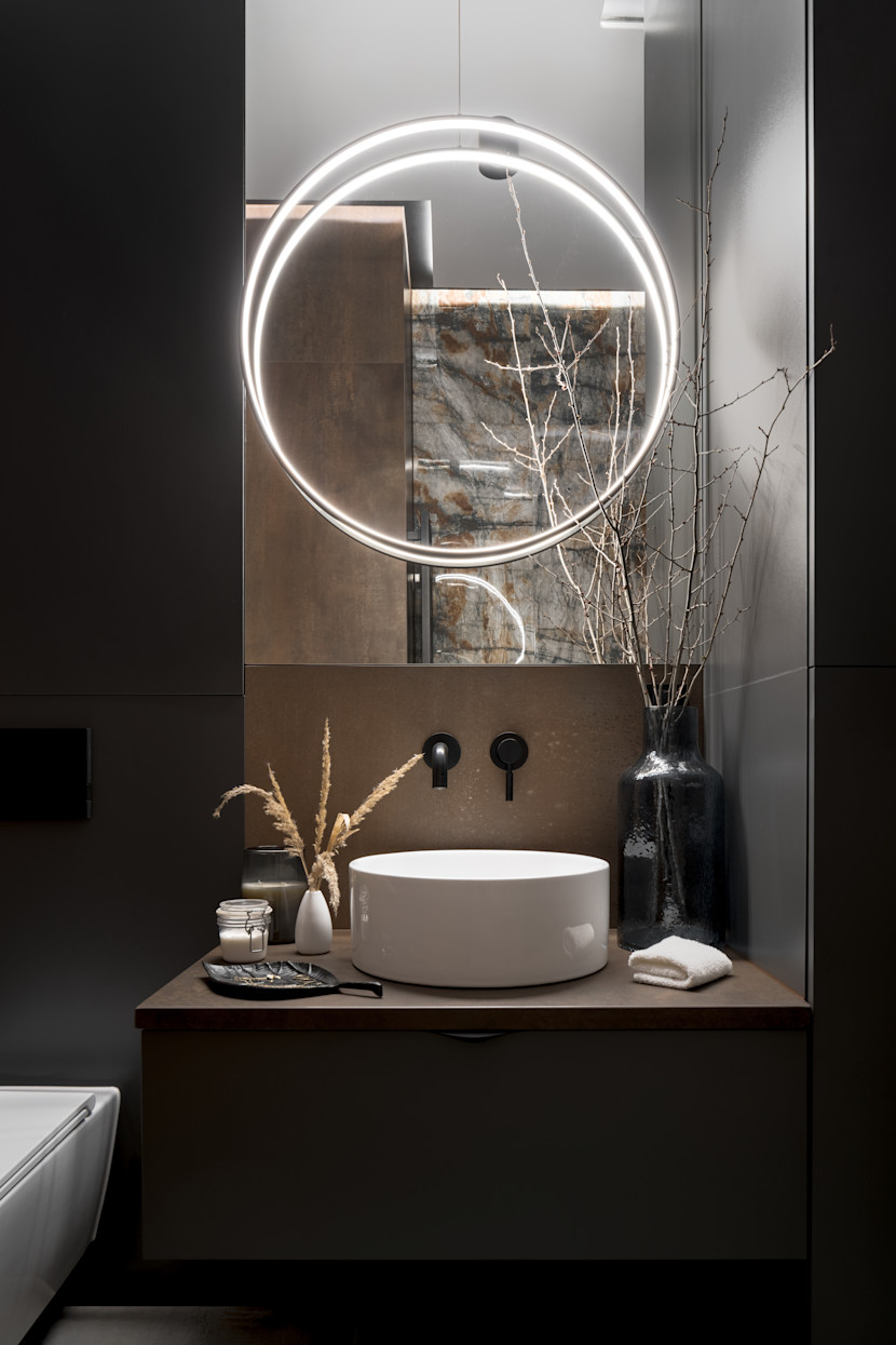 Powder room with bowl sink and lit, circular mirror