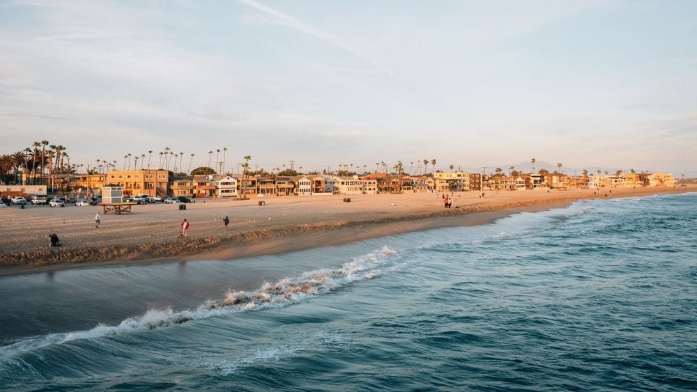 View from the water of a clean beach with people and buildings along the sand.