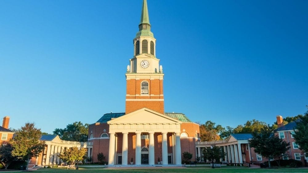 A brick and stone chapel with white columns in front and a green turret.