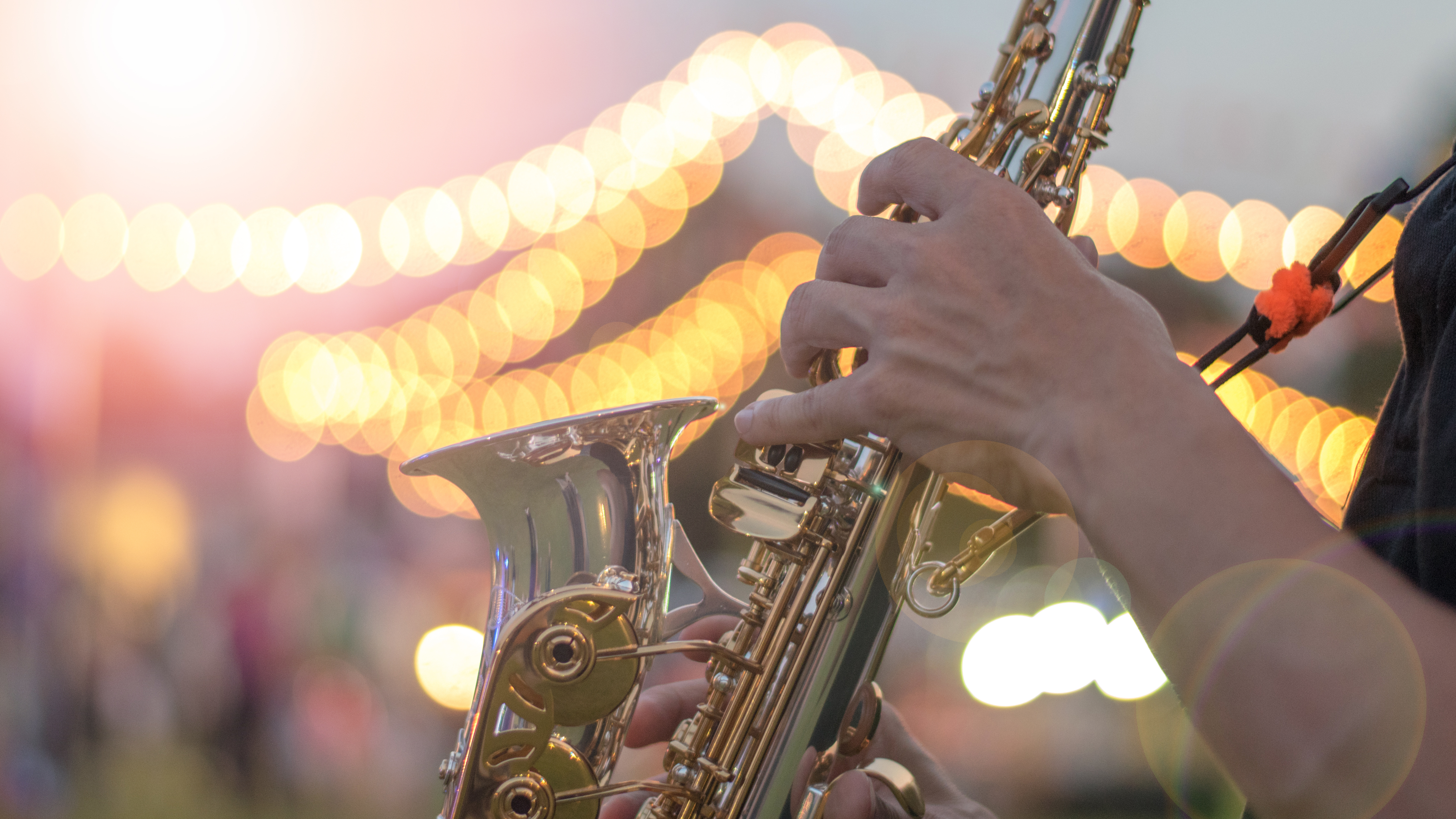 Saxophonist playing music at festival with lights in the background