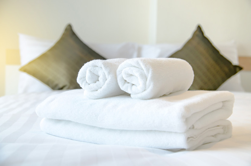 Fluffy, white rolled bath towels on a bed in a guest bedroom