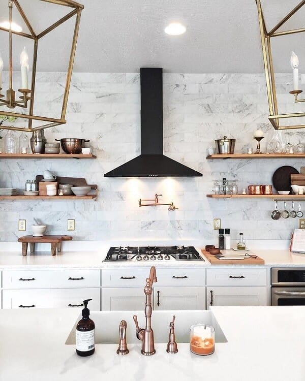 Kitchen with white cabinets, black hood, and hardware in different tones of gold