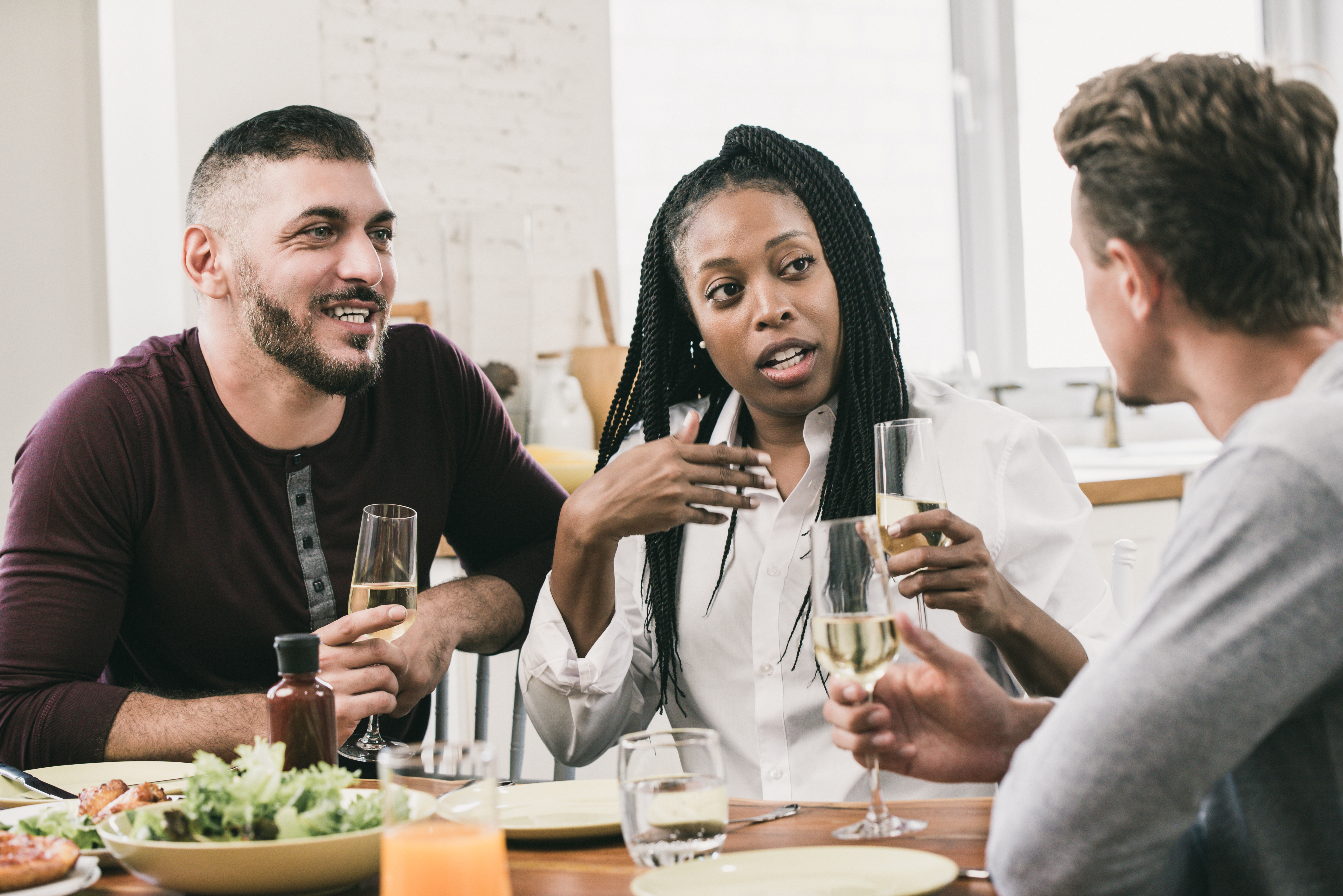 a diverse group of people talking at a dinner table