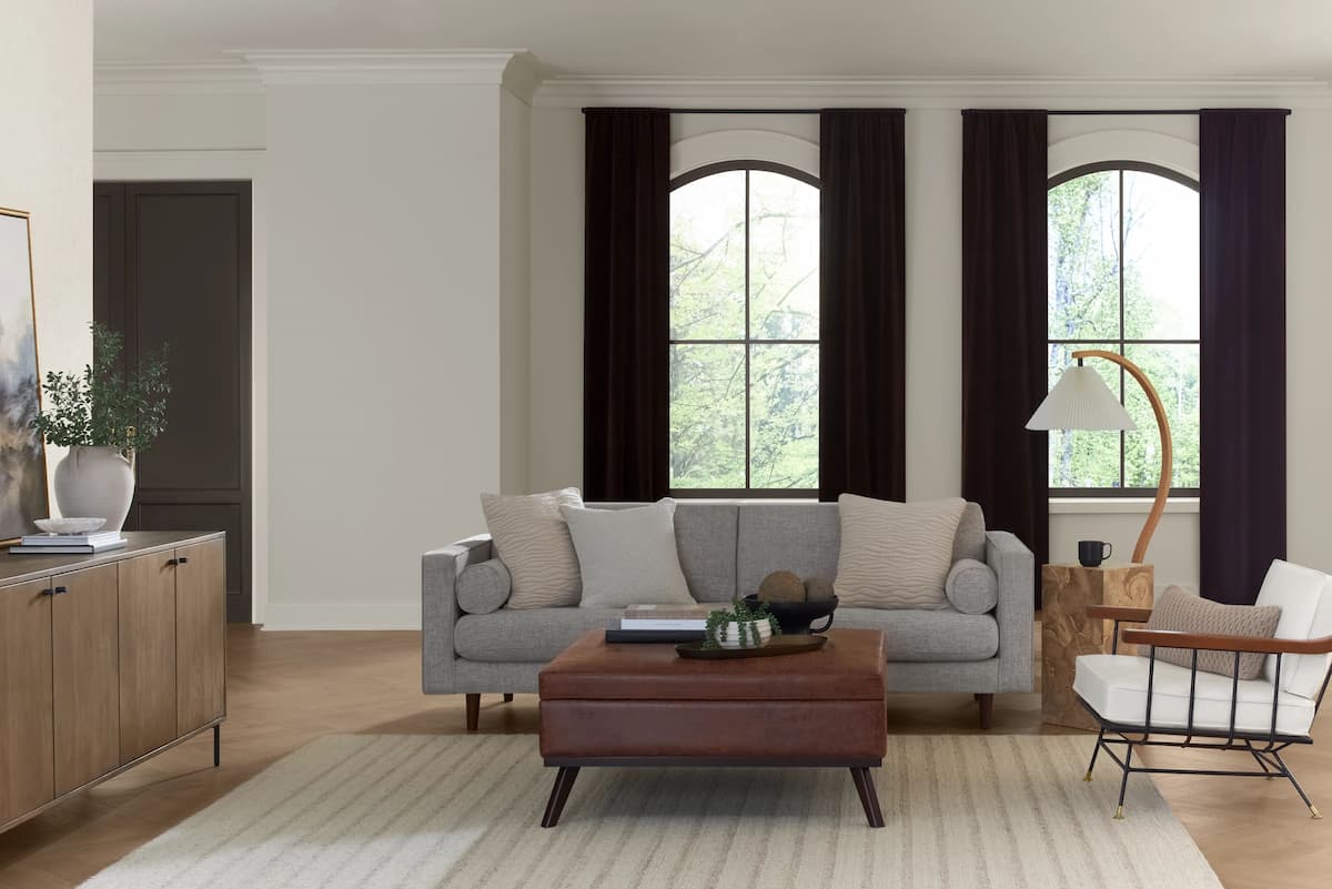 living room in quiet luxury style, with Creamy from Sherwin Williams on the walls, dark window treatments and neutral color palette