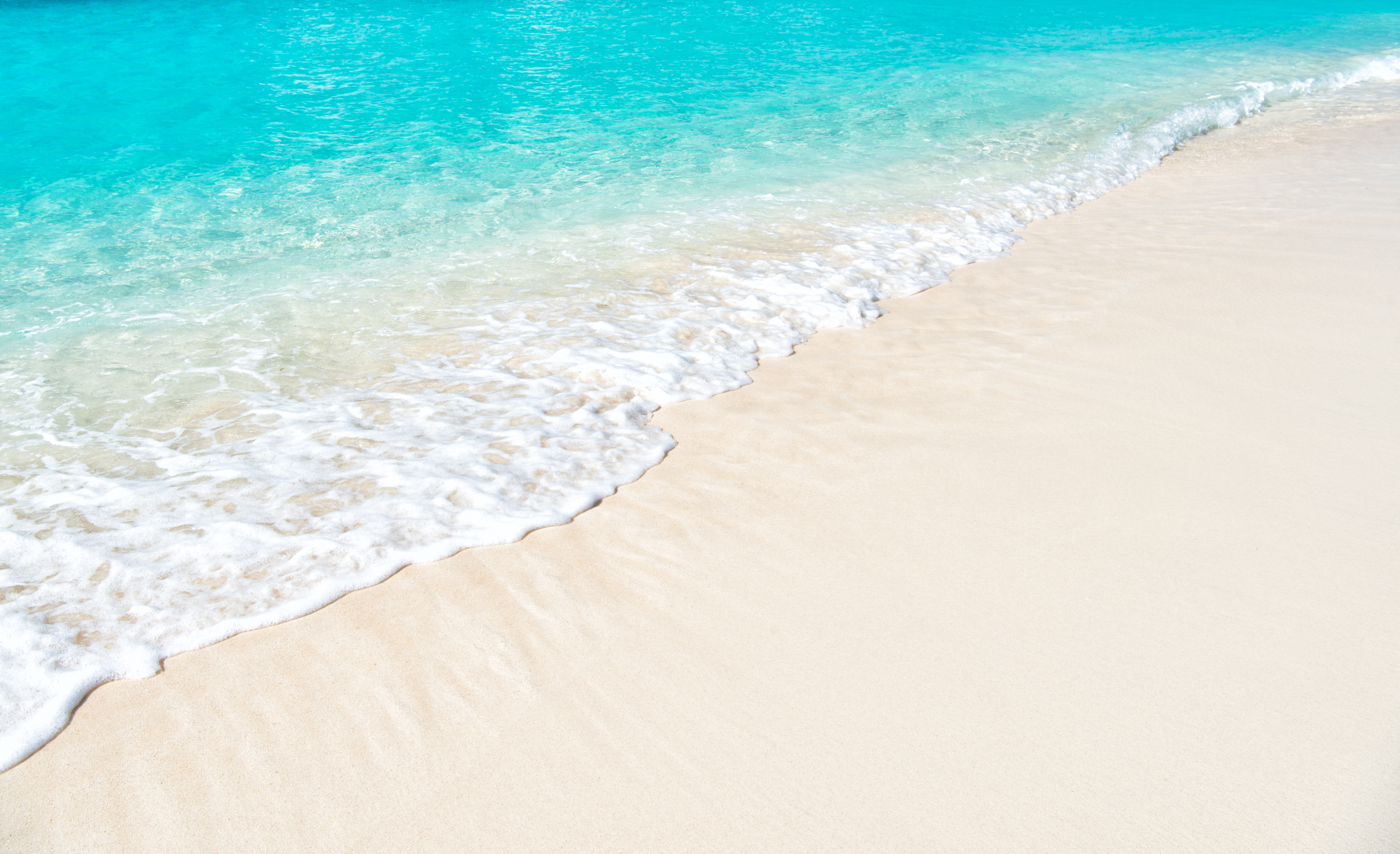 waves hitting the white sandy beach on a sunny day