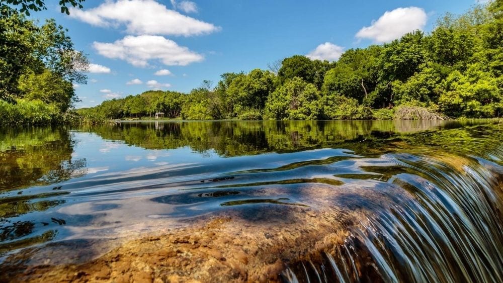 A small waterfall on a river with trees lining both banks.