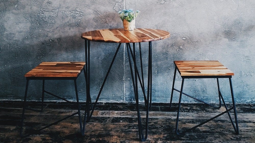 Table and stools made of light wood and black metal.