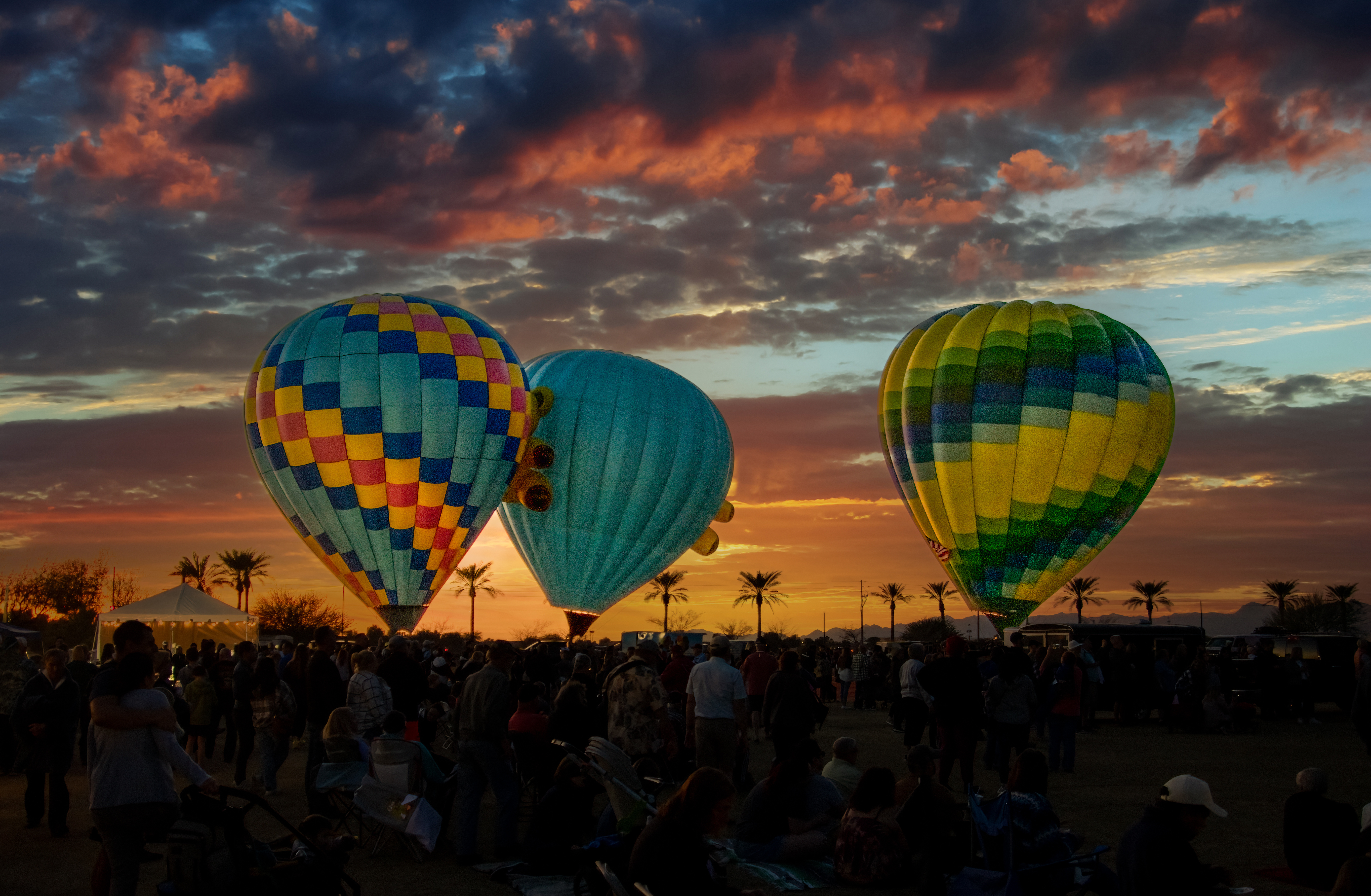 colorful hot air balloons on the ground against a cloudy sunset sky