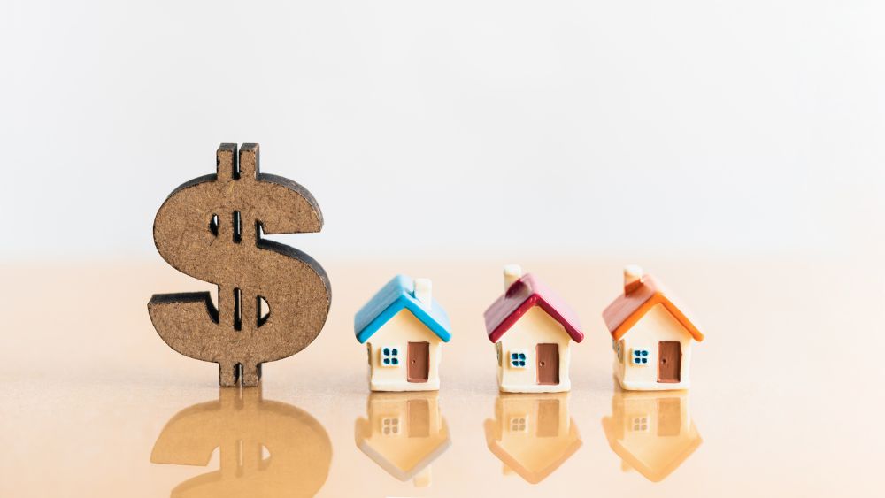 Large wooden dollar sign next to 3 small ceramic houses