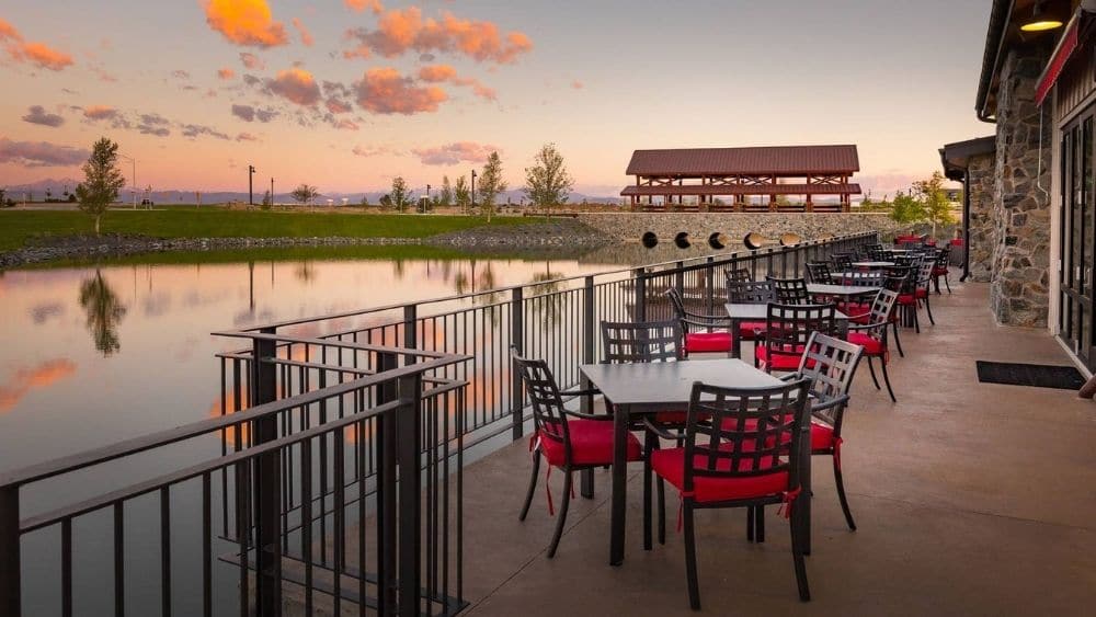 A boardwalk with patio tables lining a lake.