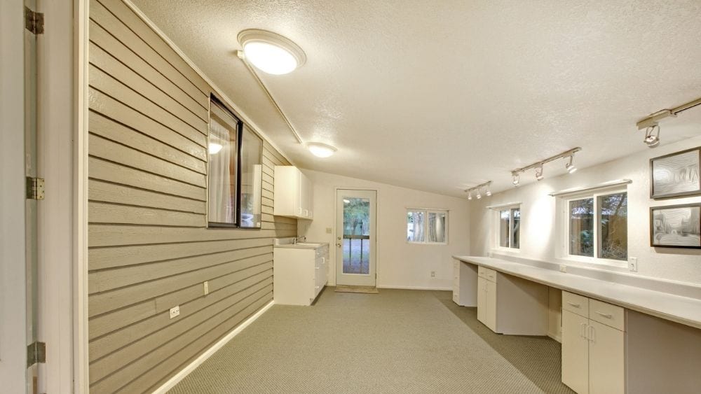 A room with a slanted shed roof and built-in desks on one side.
