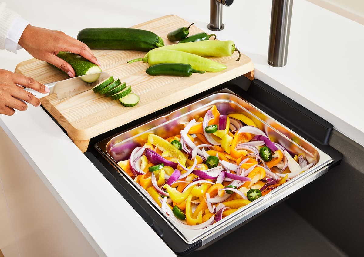 workstation sink that combines cutting board and a drainer, with someone chopping vegetables