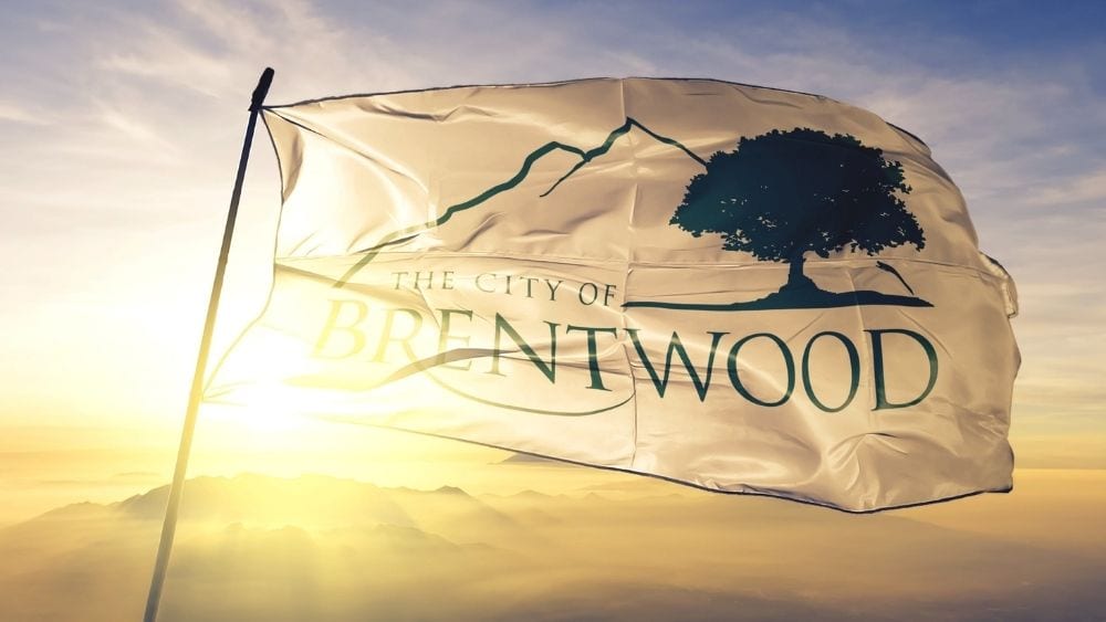 A white flag that says “City of Brentwood” with a large oak tree on it.