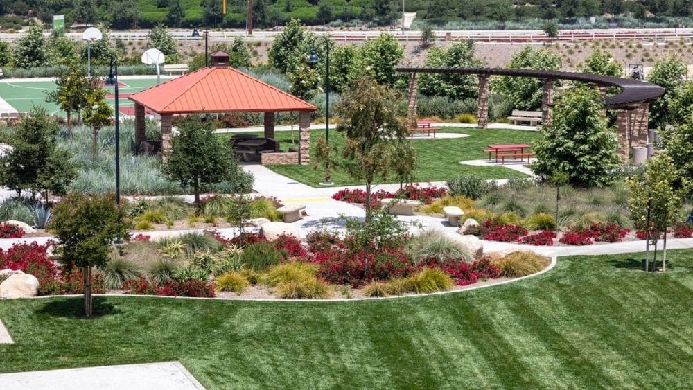 Distant view of a manicured park with walking paths and a pavilion with seating underneath.