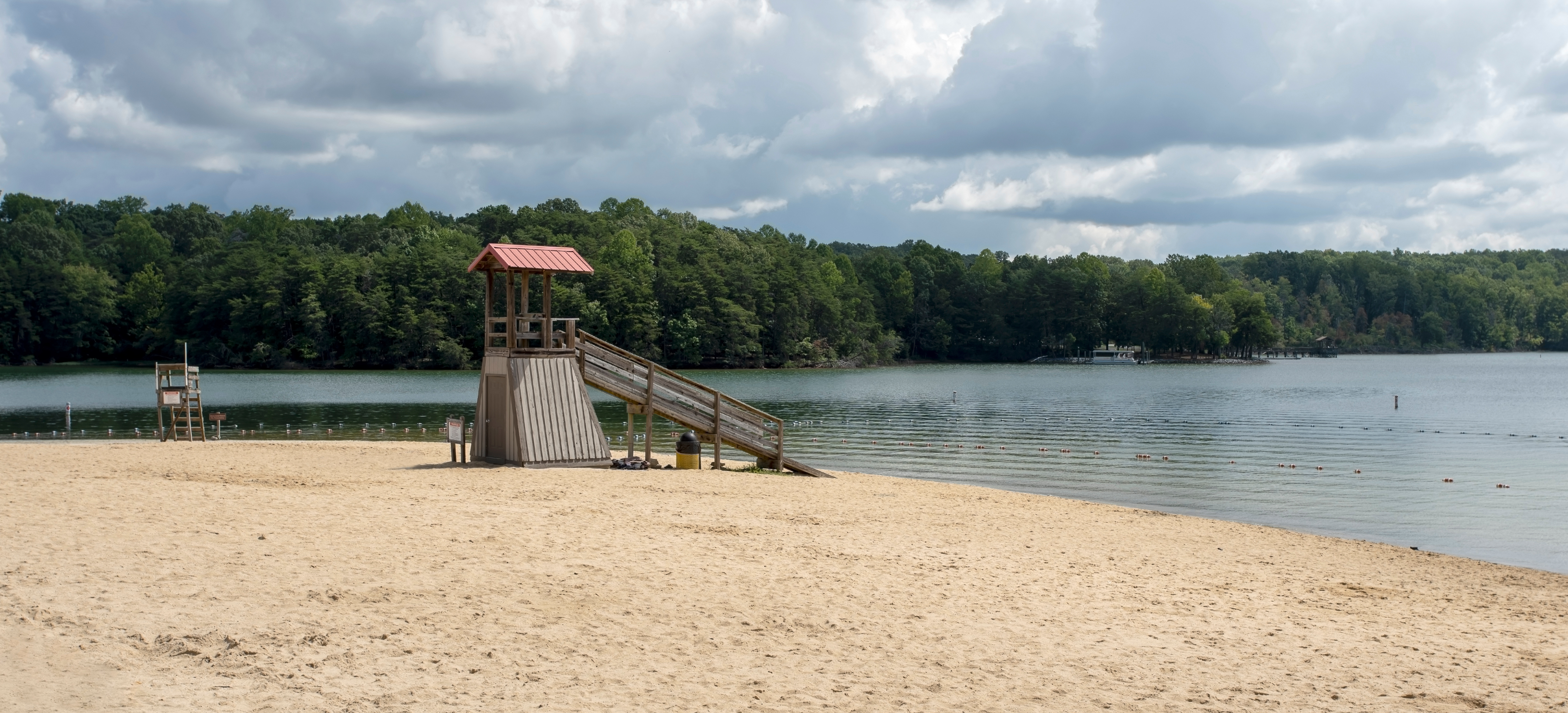 beach with a lifeguard stand along wooded lake