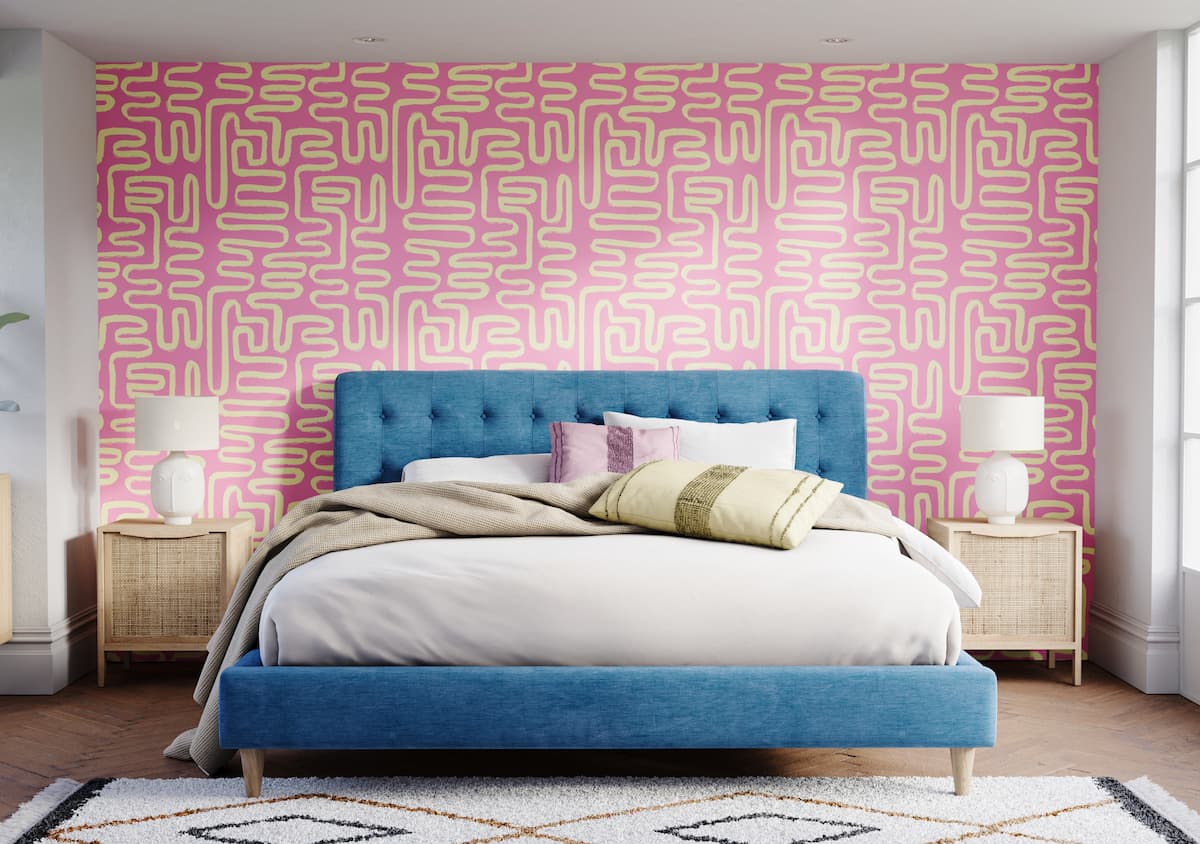 bedroom with pink accent wall, with blue headboard and geometric rug