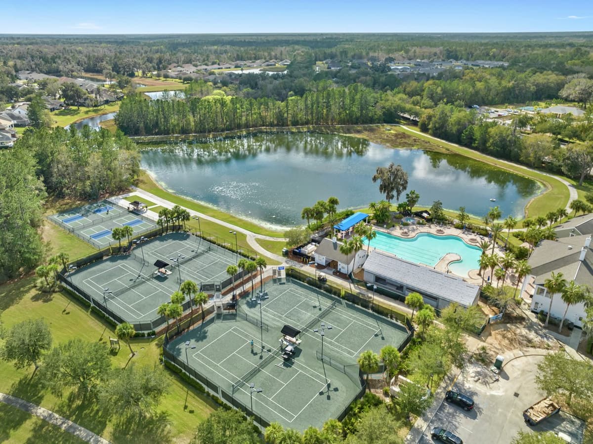 Skyview of multiple tennis courts, a lake and a swimming pool on a Terrata Homes property