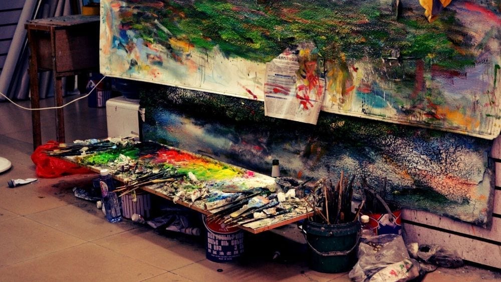 Art studio with large painting and several brushes and paint options