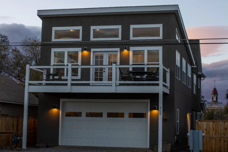 Exterior shot of contemporary style home with flat, boxy roofline, rectangular windows and raised balcony over the garage