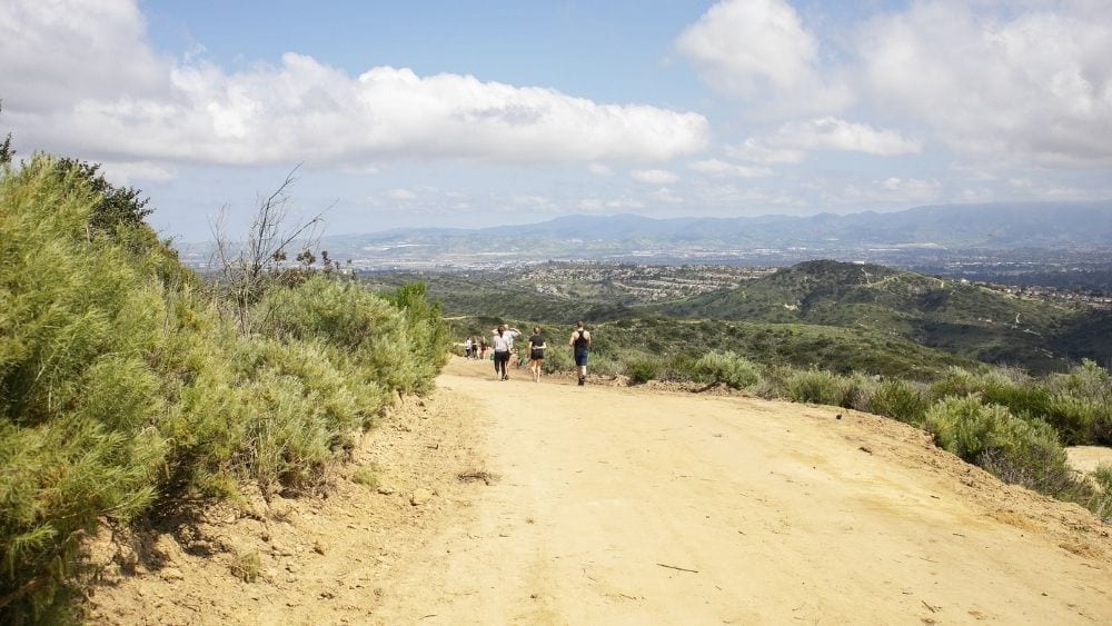 Looking down a hill toward more hikers walking a path on a mountain.