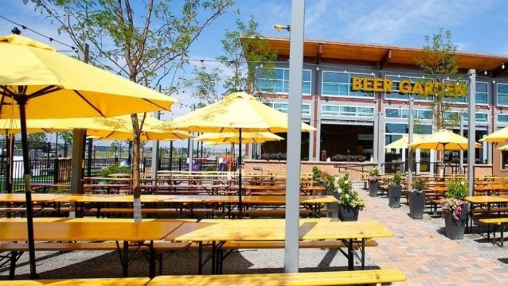 Beer garden patio with yellow umbrellas over picnic benches.