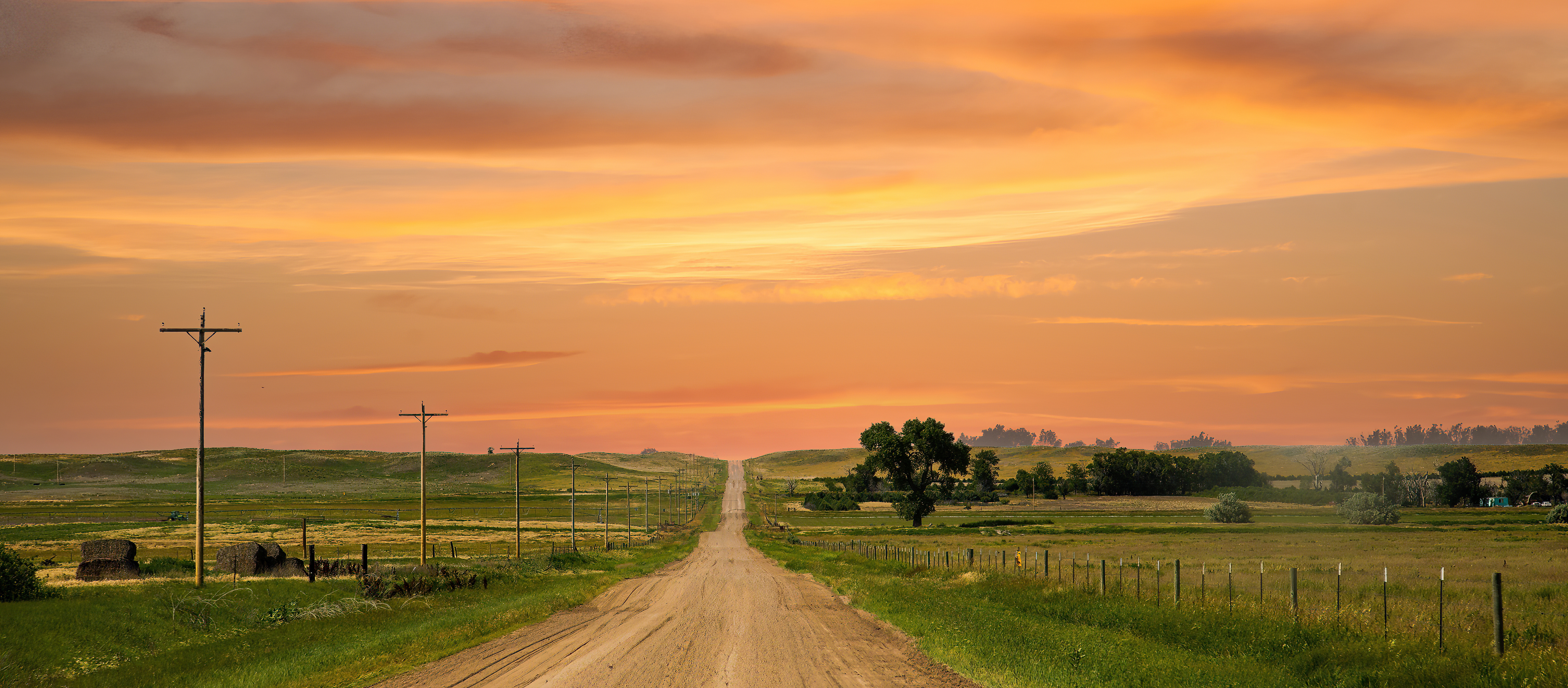 rural road flanked by farmland and a beautiful sunset