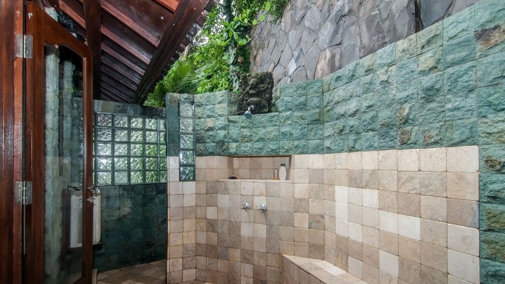 Luxurious outdoor shower with stone and tiled walls.