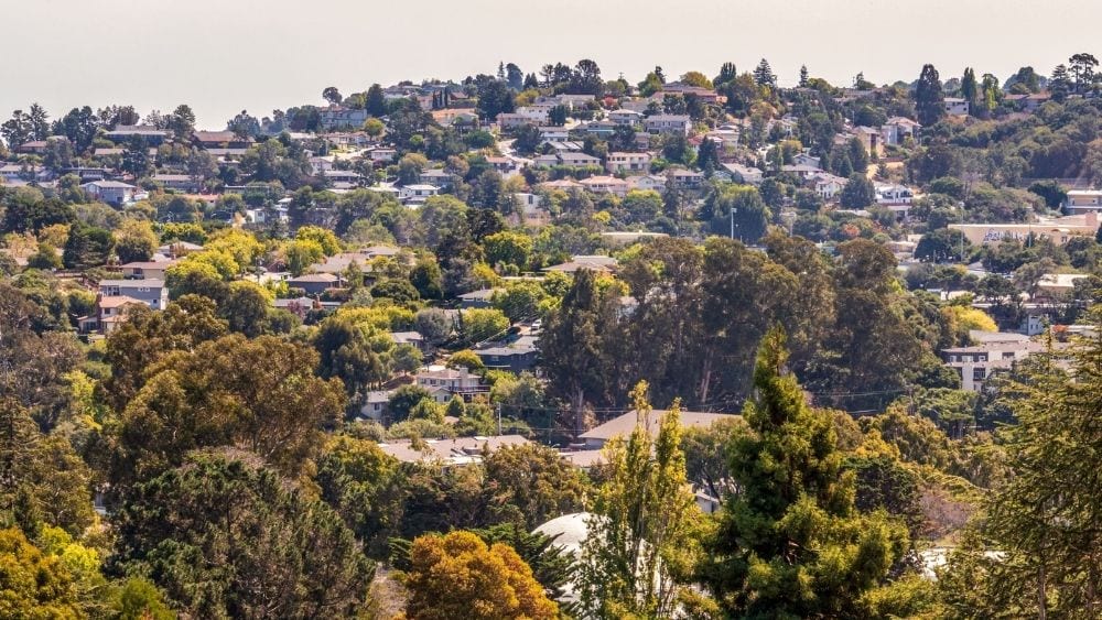 Homes dotting the hills and valleys, mixed with colorful trees.