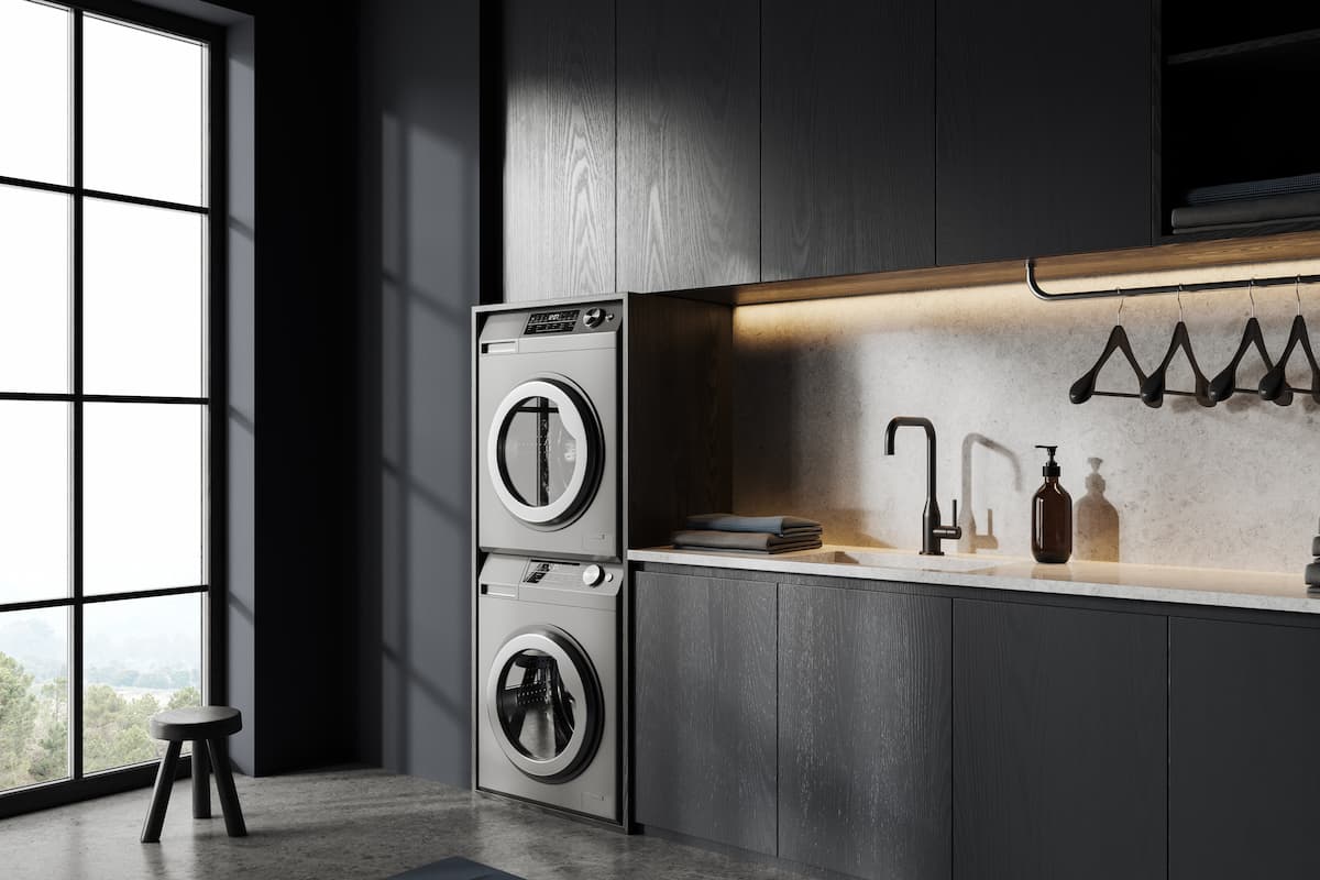 laundry room with stacked, black stainless steel washer and dryer, flat panel cabinetry and large window