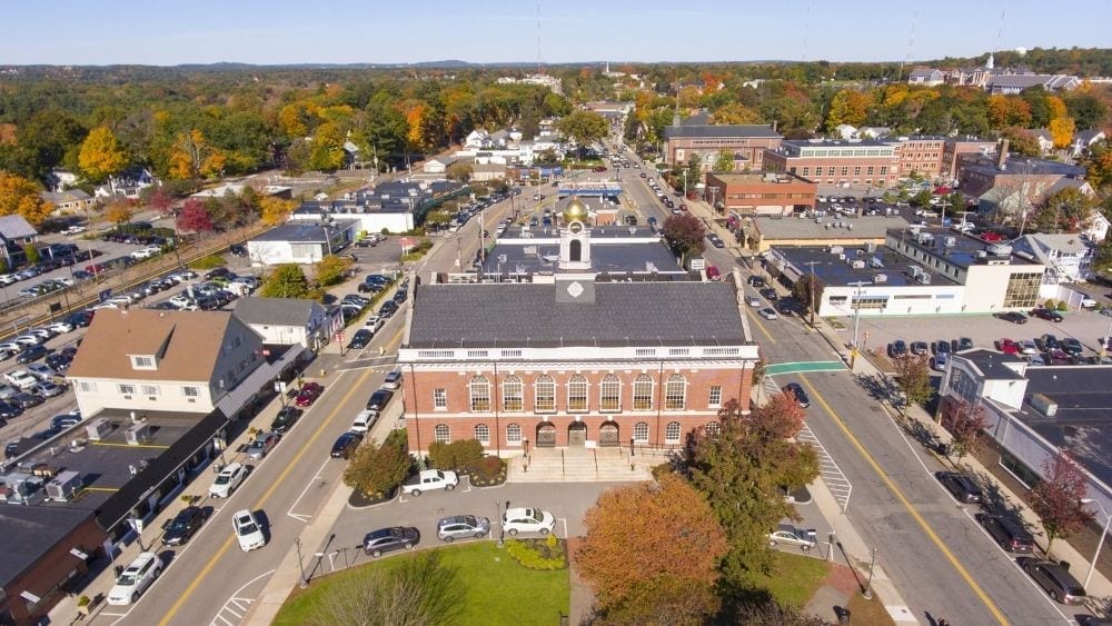 Aerial view of a historic building with a golden turret at the top, set between two busy streets.
