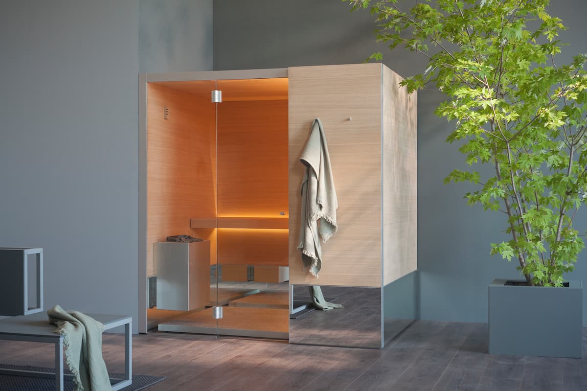 indoor sauna with one door open, with robe hung on a hook, and large plant nearby