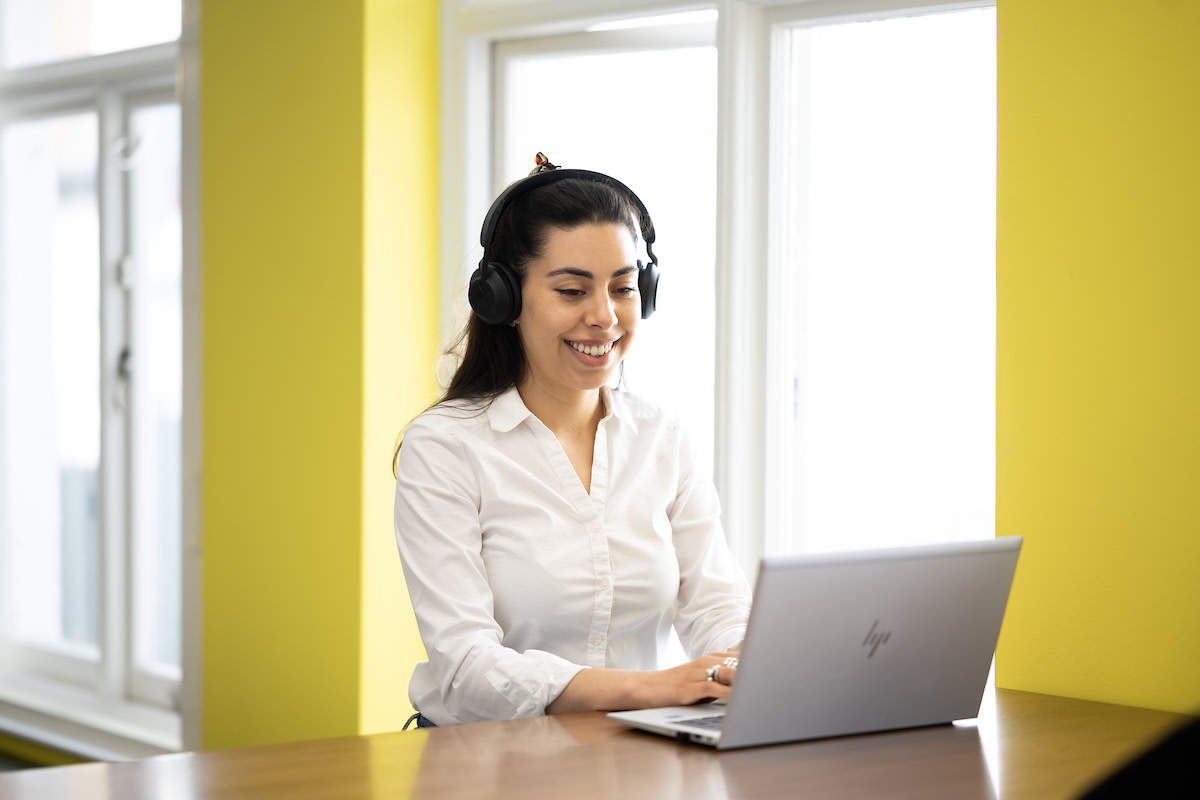 A woman in a coaching session smiling at her laptop.
