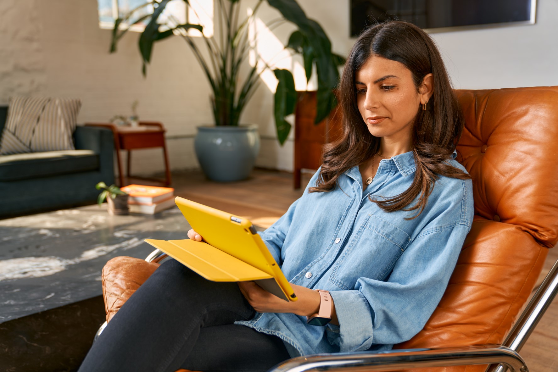 A woman sitting on a chair looking at an ipad.