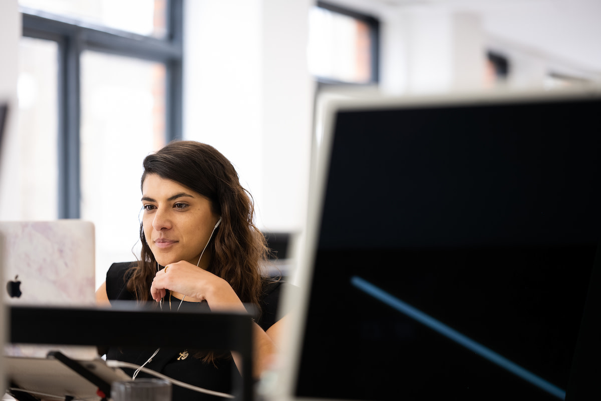 Close-up of woman focusing on work at her desk with earphones in