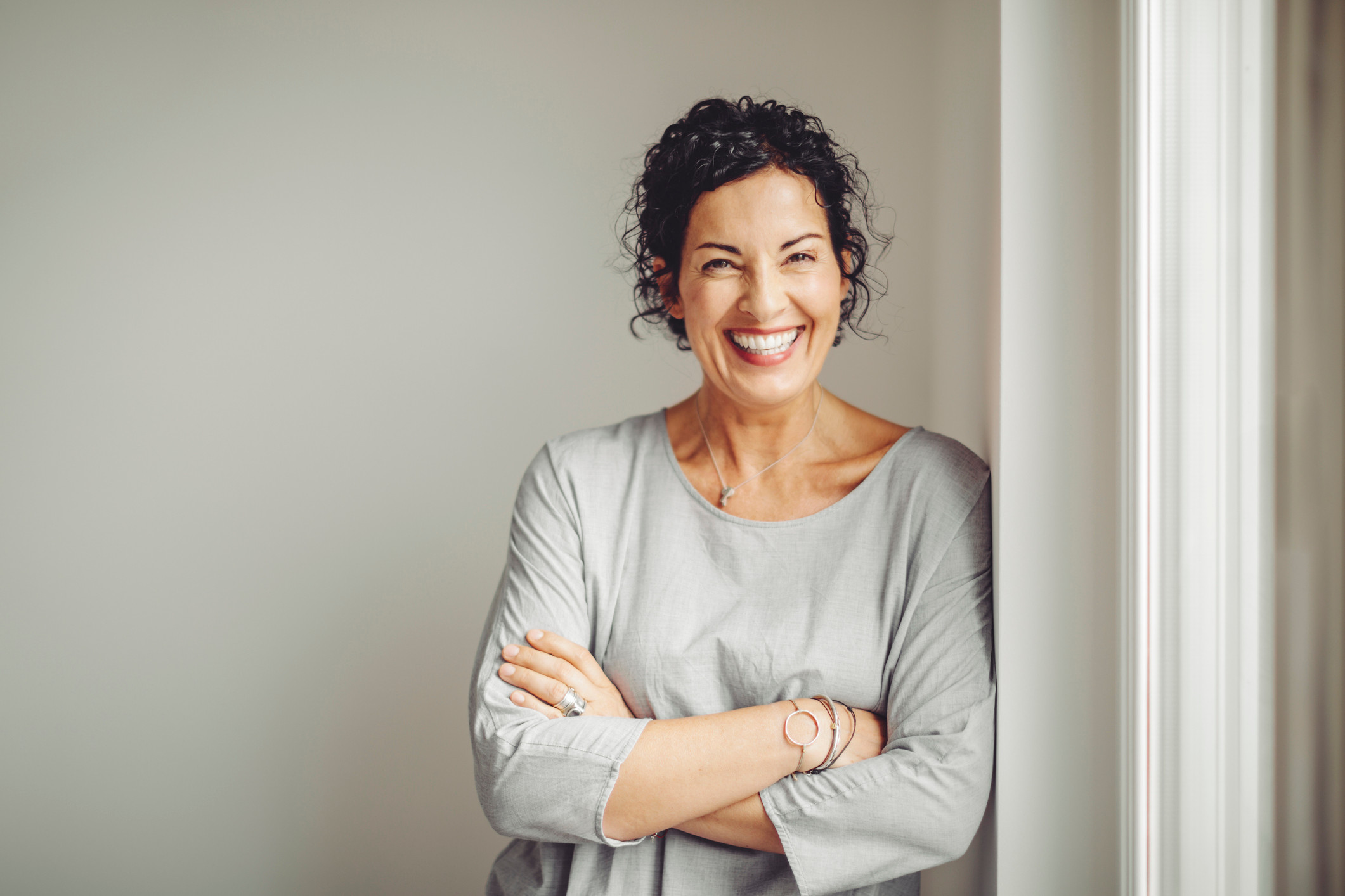 Femme en haut gris souriant à la caméra