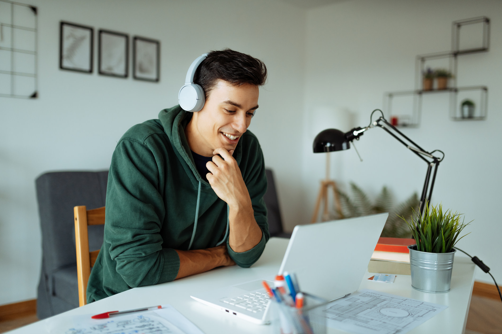 Man at white desk, with white laptop and white headphones